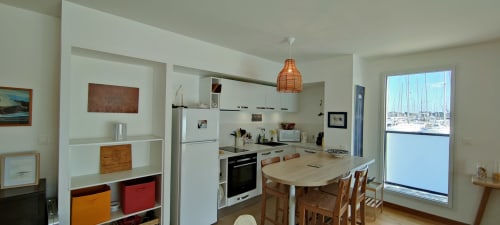 Cuisine moderne et salle à manger de Mer et Maisons à La Trinité sur Mer avec vue sur la marina par les grandes fenêtres