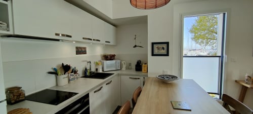 Cuisine moderne aux placards blancs, comptoir de bois et vue sur le port à Mer et Maisons, La Trinité sur Mer