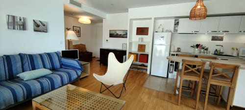 Studio moderne à Mer et Maisons en Trinité sur Mer avec canapé rayé bleu, chaise blanche, cuisine et boiseries
