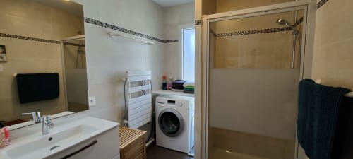 Salle de bain moderne avec douche, lavabo, miroir et lave-linge à l'hôtel Mer et Maisons à La Trinité sur Mer