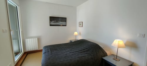 Chambre minimaliste de l'hôtel Mer et Maisons à La Trinité sur Mer avec literie foncée, lampes d'appoint et décoration bord de mer