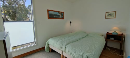 Chambre lumineuse à Mer et Maisons avec literie verte, table de nuit en bois et vue sur l'océan à La Trinité sur Mer