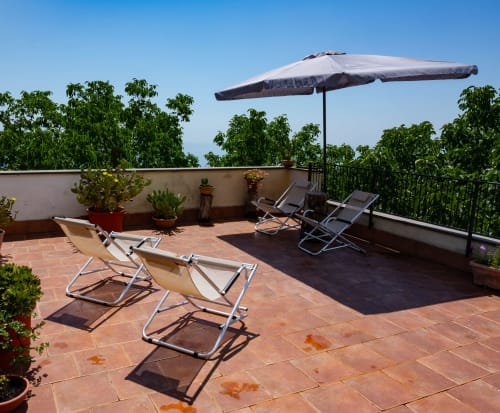 Terrazza sul tetto dell'Hotel Milomax con lettini, ombrellone e vista sulla campagna di Milo, Italia