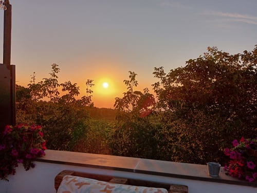 Vista del tramonto dal balcone dell'Hotel Milomax con fiori in fiore e paesaggio rurale a Milo, Italia
