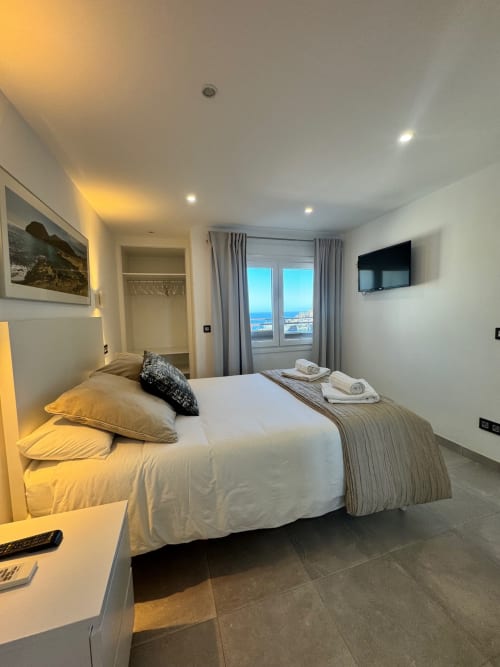 Moderno dormitorio de hotel en El Faro De Los Genoveses con vista al mar, ropa de cama blanca, TV de pantalla plana y terraza costera en Almería