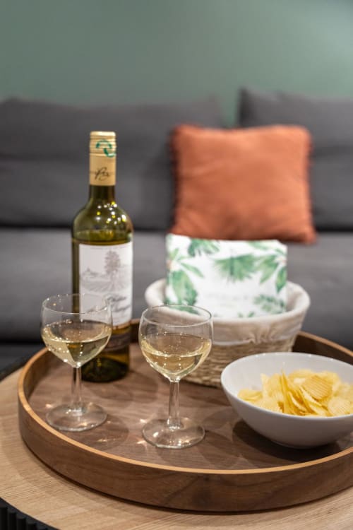 White wine and chips served in Bordeaux apartment with cozy sofa and orange pillow decor