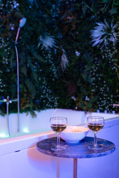 Elegant evening poolside setting at Wellkhome Bordeaux with wine glasses, white bowl, and illuminated garden backdrop
