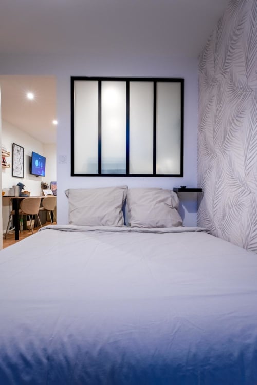 Modern bedroom at Wellkhome Bordeaux with queen bed, work desk, TV, and framed window art with city view