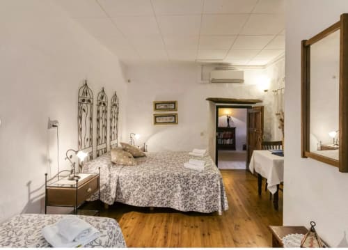 Dormitorio amplio en el B&B Can Gat Vell de Girona con cama de hierro forjado, suelos de madera y comodidades modernas.