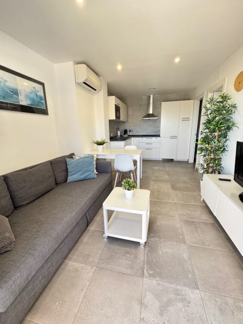 Moderna sala de estar en El Faro De Los Genoveses con sofá gris, cocina blanca y comedor en San José, Almería