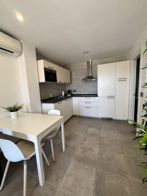 Cocina y comedor moderno del apartamento El Faro De Los Genoveses, San José Almería, con gabinetes blancos y azulejos grises
