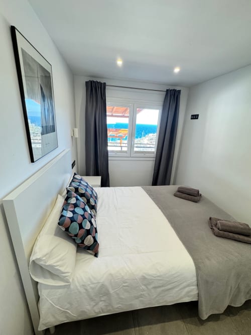Moderno dormitorio con vistas al mar en El Faro De Los Genoveses, San José Almería, con cama, televisor y vistas a la costa