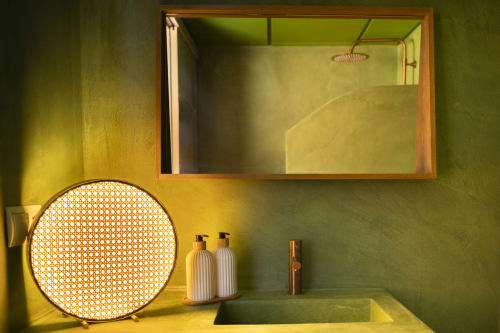 Lujoso cuarto de baño del hotel Formentera Especial con paredes amarillo-verdosas, espejo redondo y modernas comodidades con vista al mar
