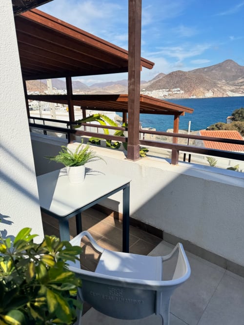 Terraza con vistas al mar en El Faro De Los Genoveses, Almería, con pérgola de madera, plantas en macetas y montaña costera