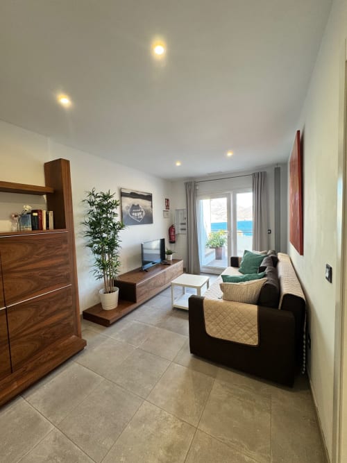 Moderna sala de estar en El Faro De Los Genoveses con vista al mar, mobiliario confortable, TV y acceso a terraza