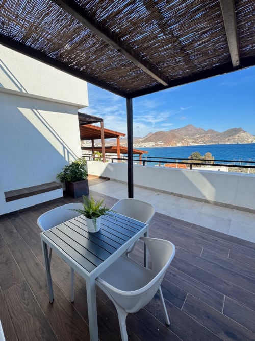 Terraza frente al mar del apartamento El Faro De Los Genoveses con vistas al mar, mesa de comedor y sierra al fondo en Almería.