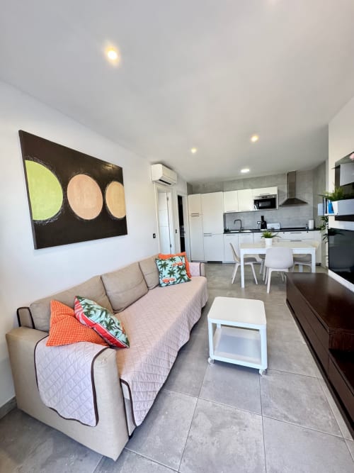 Moderna sala de estar en El Faro De Los Genoveses con sofá beige, mesa de comedor blanca y cocina abierta en San José