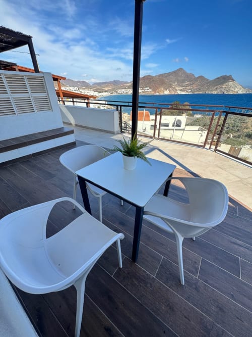 Soleada terraza costera en El Faro De Los Genoveses con muebles blancos, vistas al mar y montañas más allá de San José, Almería