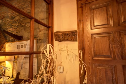 Entrada secreta del arte en Can Gat Vell B&B en Girona, puerta de madera con señalización rústica y plantas secas
