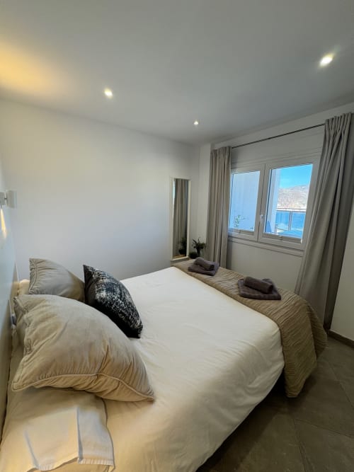 Moderno dormitorio luminoso con vista al mar en El Faro De Los Genoveses, San José, Almería - cama blanca, cortinas beige, vistas costeras