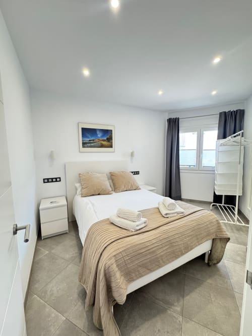 Habitación moderna en El Faro De Los Genoveses con vistas al mar, cama doble, mesilla blanca e iluminación brillante