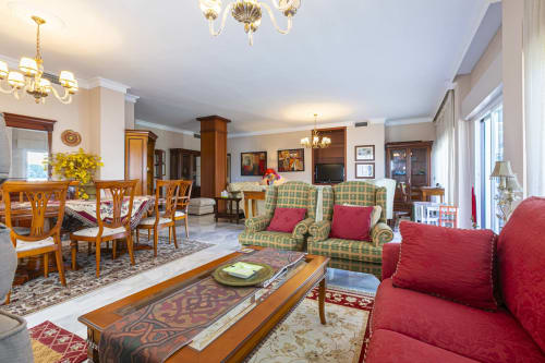 Elegant living room in Royal Gardens apartment, Marbella with red and green furnishings, wooden furniture, chandeliers, and