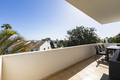 Spacious terrace at Marbella Home Rentals in Nueva Andalucía with sea views, outdoor dining, and Mediterranean landscape