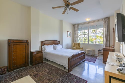 Spacious bedroom with wooden furniture and pool view at Marbella Home Rentals, Nueva Andalucía apartment