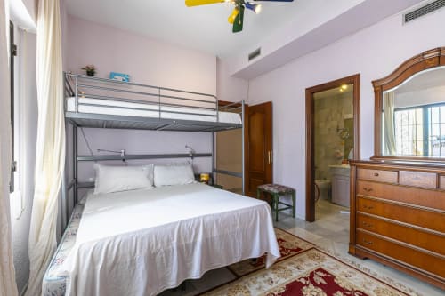 Spacious bedroom in Marbella apartment with bunk bed, wooden dresser, and ensuite bathroom