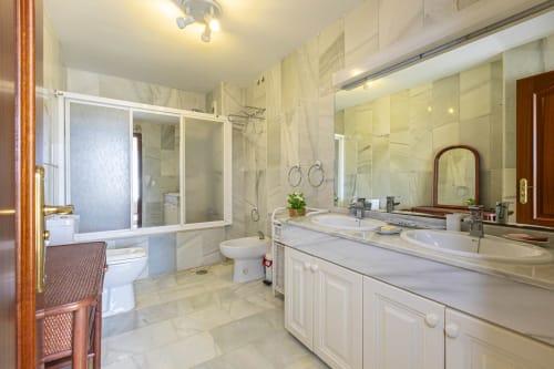 Luxury bathroom in Royal Gardens apartment, Marbella with double vanity, marble tiles, and modern fixtures