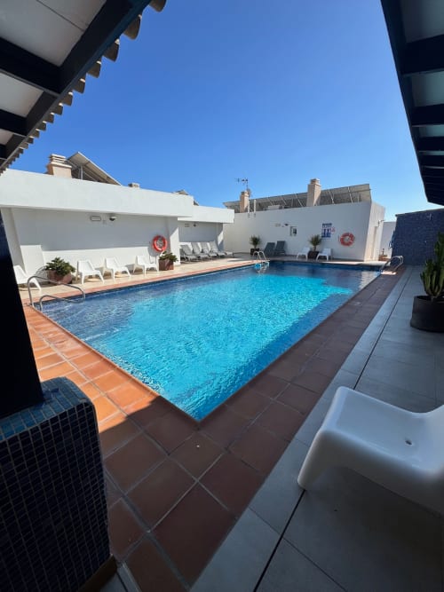 Piscina en la azotea del hotel El Faro De Los Genoveses en San José, Almería con agua azul cristalina y tumbonas blancas
