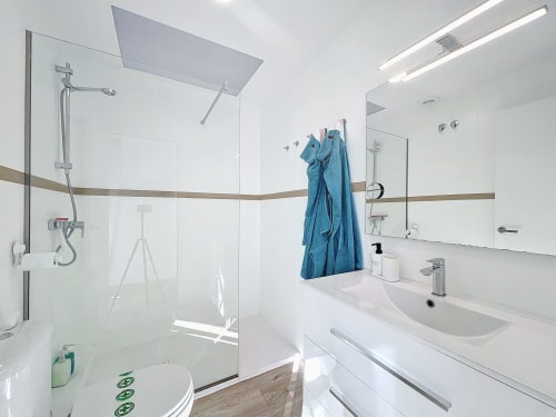Baño moderno en la casa rural La Vela en Estartit con ducha a ras de suelo, lavabo blanco y vistas al jardín