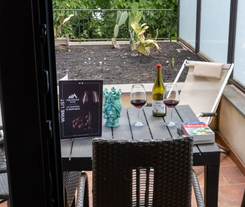 Degustazione di vini all'Hotel Milomax con bicchieri, bottiglia e menu della cantina con vista sulla terrazza del giardino