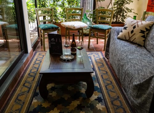 Lounge dell'Hotel Milomax con sedie in legno, bottiglie di vino e camino che si affaccia sulla terrazza a Milo, Italia