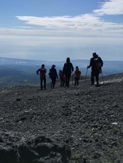 Gruppo di escursionisti su terreno vulcanico con vista panoramica della valle vicino all'Hotel Milomax a Milo, Sicilia