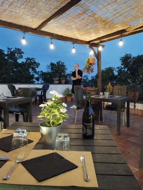 Elegante area ristorazione sul tetto dell'Hotel Milomax con tavoli apparecchiati, fiori in vaso e atmosfera serale sotto pergolato in legno