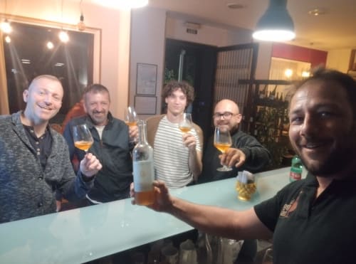 Cinque uomini che si divertono con drink e socializzano al bar dell'Hotel Milomax a Milo, IT