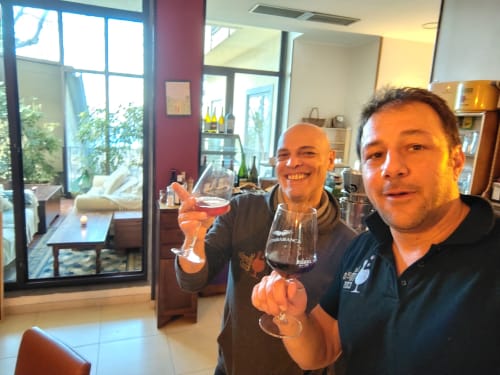 Due uomini brindano con bicchieri di vino all'Hotel Milomax a Milo, in Italia, in un'elegante sala da pranzo con vista sulla terrazza.