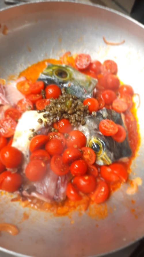 Pesce fresco con bacche rosse in una padella all'Hotel Milomax, Milo CT