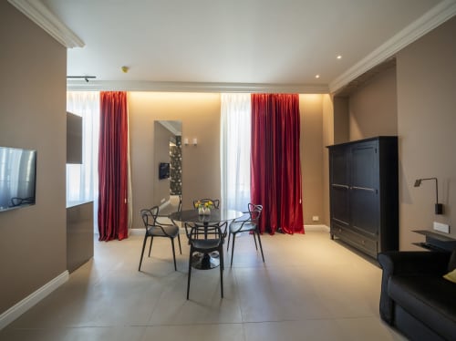 Suite moderna del Seven Suites Sanremo con zona pranzo, tende rosse e arredi contemporanei