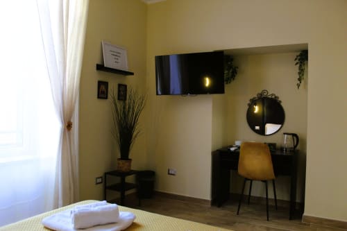 Camera moderna al Blackwoody Contemporary Hospitality di Napoli con pareti gialle, TV schermo piatto, scrivania, specchio e vista città