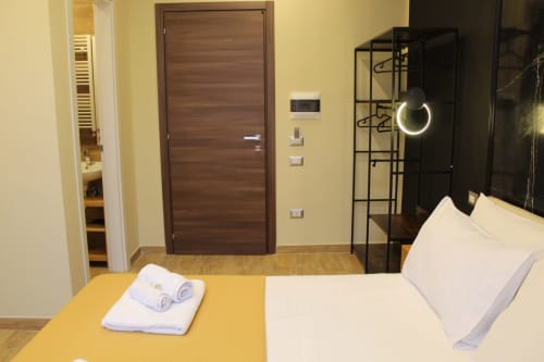 Camera moderna a Blackwoody BCH Toledo, Napoli con parete accent gialla, porta in legno scuro, biancheria bianca e vista sulla città