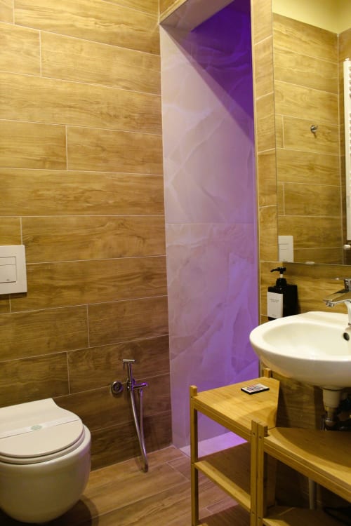 Bagno moderno al Blackwoody Contemporary Hospitality Naples con pareti rivestite in legno, lavabo bianco, wc e vetro viola