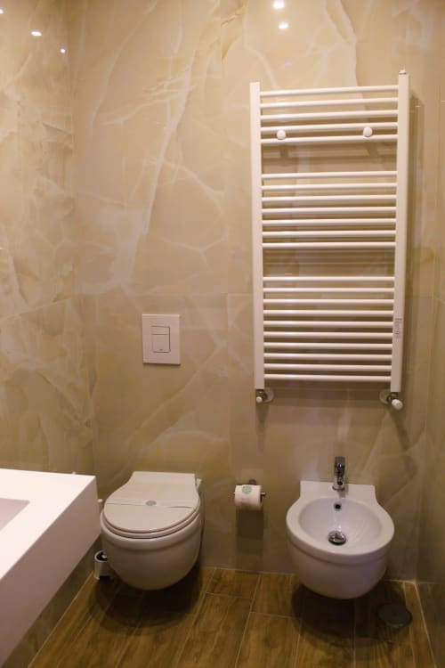 Bagno moderno dell'hotel napoletano con scaldasalviette bianco, toilet, bidet e pareti rivestite in marmo