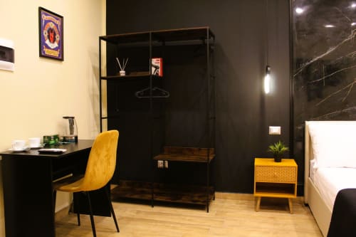 Camera moderna presso Blackwoody Contemporary Hospitality Napoli con poltrona gialla, scrivania nera, box doccia in marmo e vista città