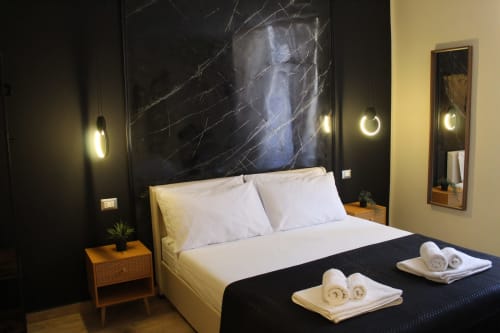 Camera moderna del Blackwoody Hotel Napoli con letto queen, biancheria bianca, testata in marmo nero, luci pendenti e vista sulla città