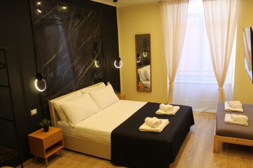 Camera moderna presso Blackwoody Contemporary Hospitality a Napoli con pareti gialle, testata in marmo nero e biancheria bianca