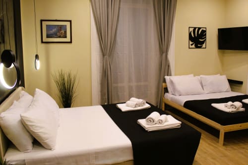 Camera quadrupla moderna presso Blackwoody Contemporary Hospitality a Napoli con due letti, pareti gialle, tende e vista sulla città