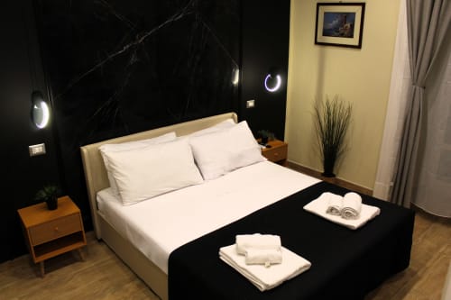 Camera moderna al Blackwoody Contemporary Hospitality di Napoli con letto color crema, parete nera in contrasto, luci LED circolari e