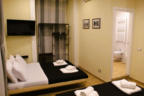Camera moderna di Blackwoody Contemporary Hospitality Napoli con letto nero, biancheria bianca, TV e bagno privato